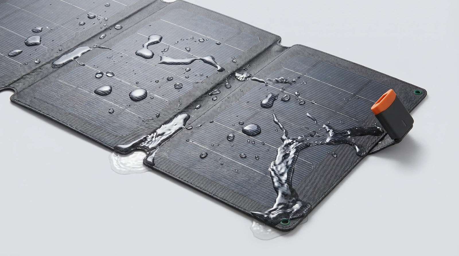 A professional feature image of the unfolded iFORWAY 36W Backpacking Solar Charger with water droplets and splashes pooling across its surface. This visually demonstrates the charger's 'Built Tough' waterproof and corrosion-proof capabilities. Featuring a high-quality ETFE surface and shockproof EVA material, this highly durable and portable solar panel ensures safe and reliable all-weather performance for camping, hiking, and emergency power supply